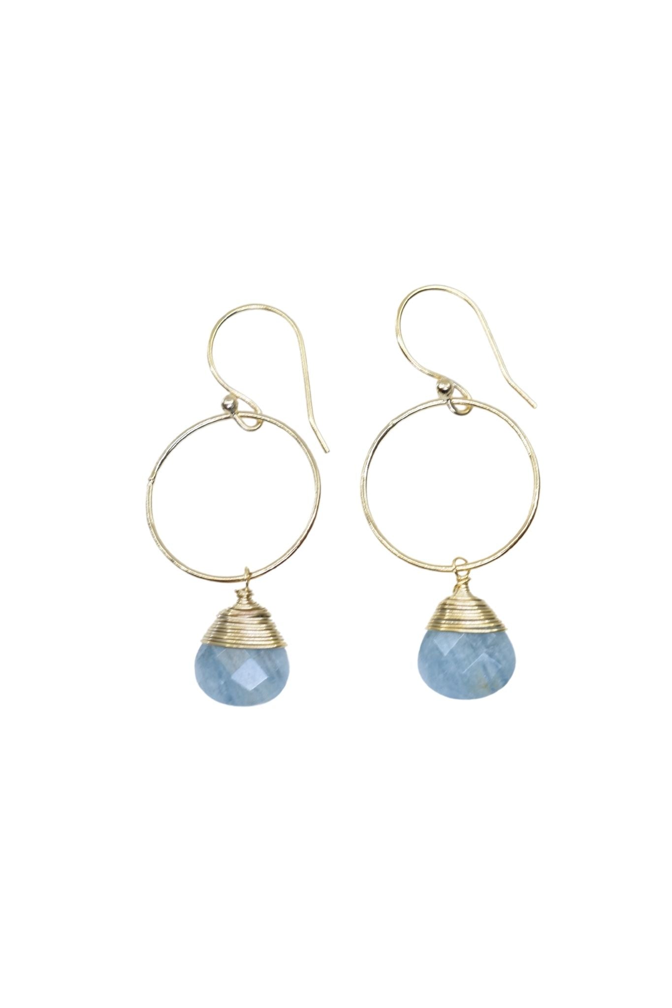 Gold hoop earrings with blue stone drops on a white background