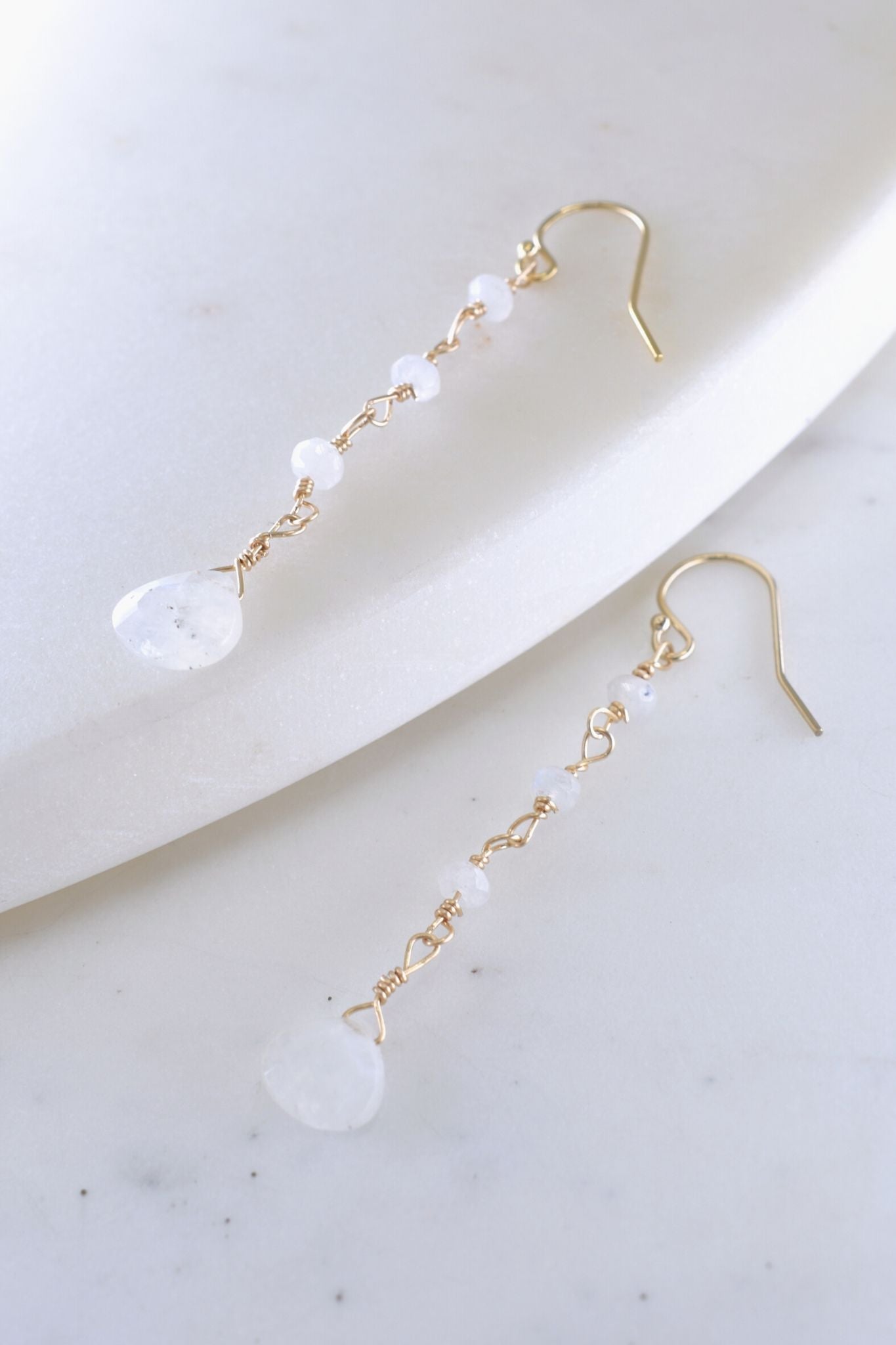 Gold earrings with clear beads on a white surface