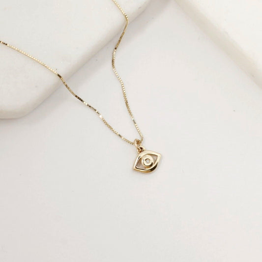 Gold necklace with a small pendant on a light beige background