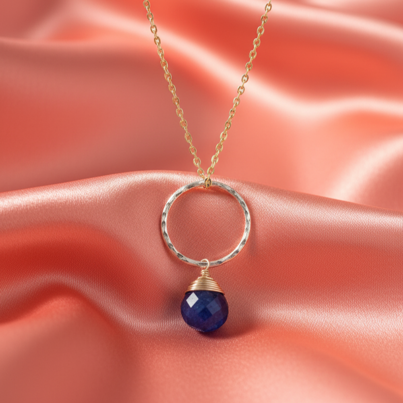 Necklace with a blue pendant on a pink satin background