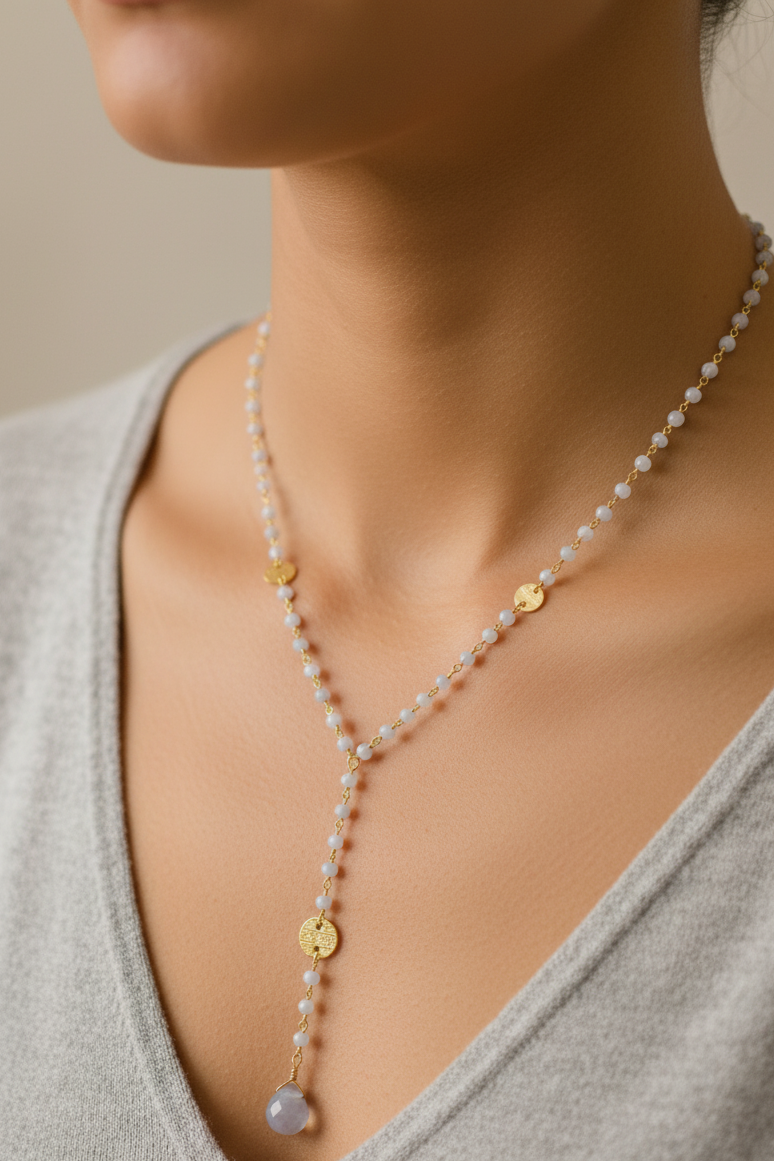 Pearl necklace with gold accents worn by a person in a gray top against a neutral background