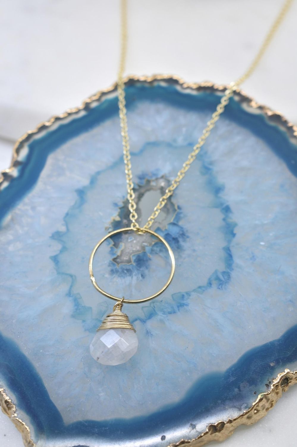 Gold necklace with a pendant on a blue and white stone surface