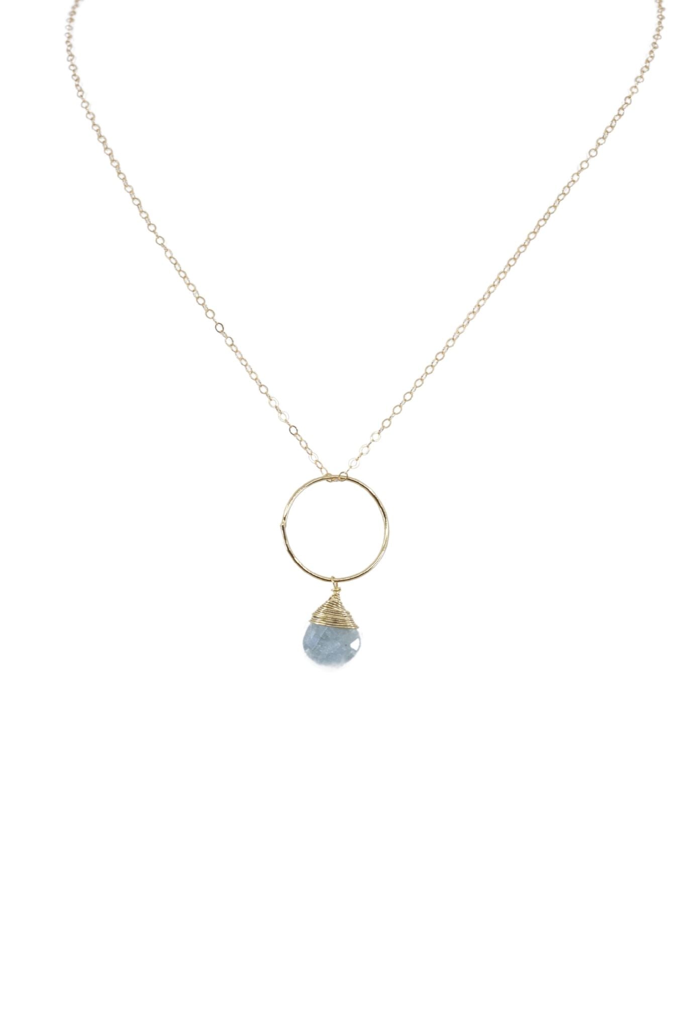 Necklace with a gold ring pendant and blue gemstone on a white background