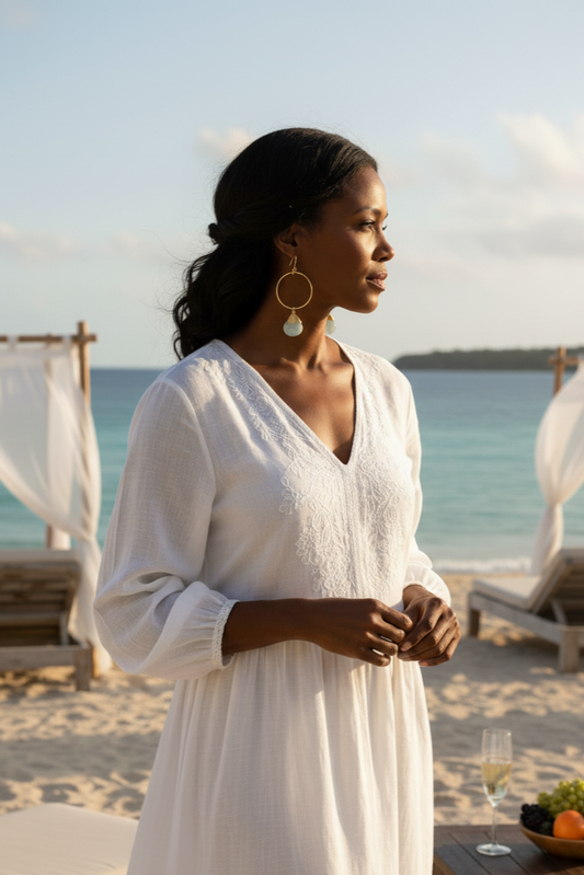 Woman in a white dress standing on a beach with ocean view