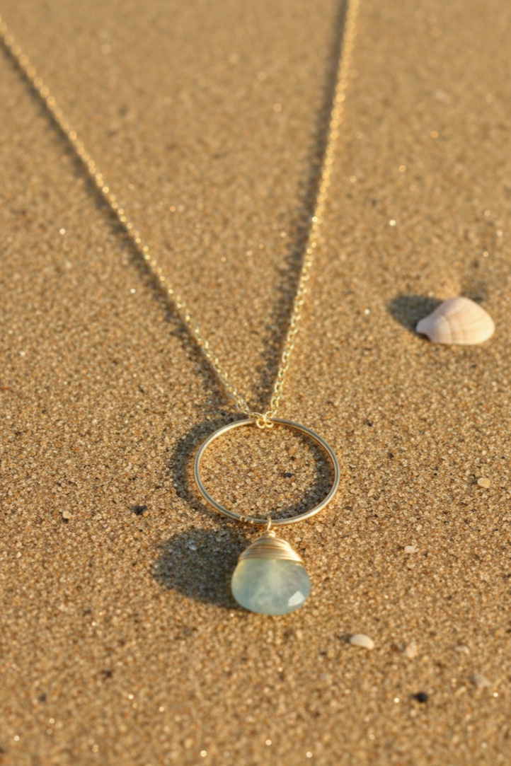 Gold necklace with a pendant on sand