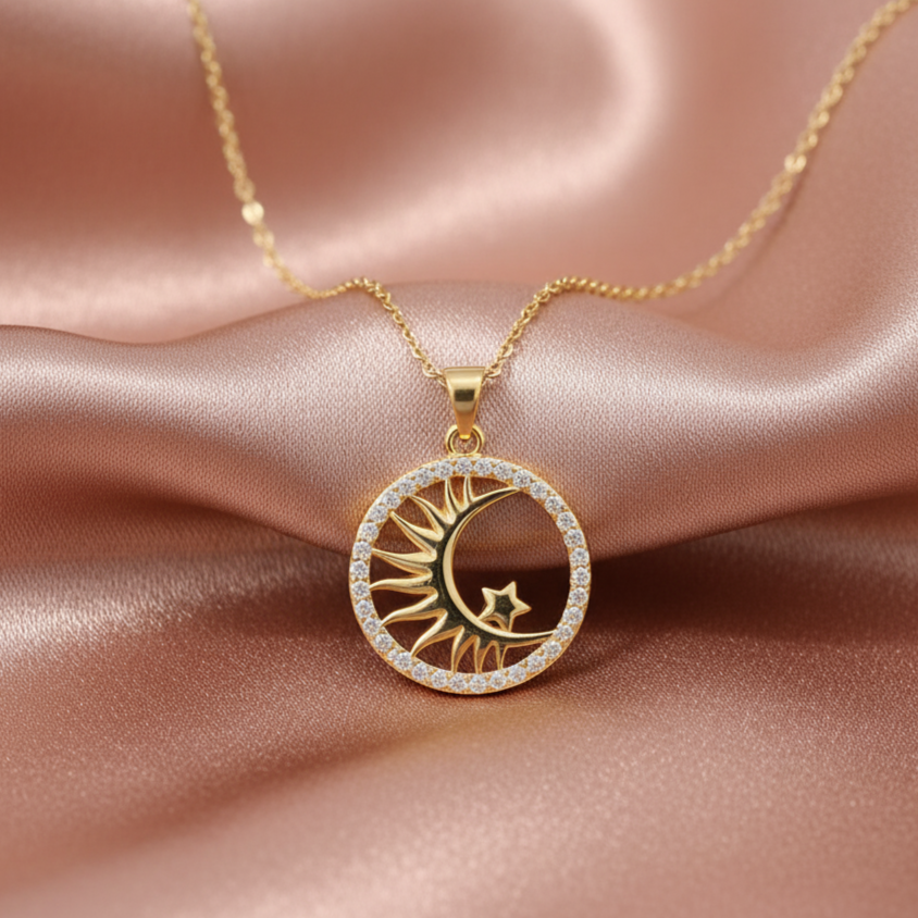 Gold necklace with a sun and moon pendant on a pink satin background