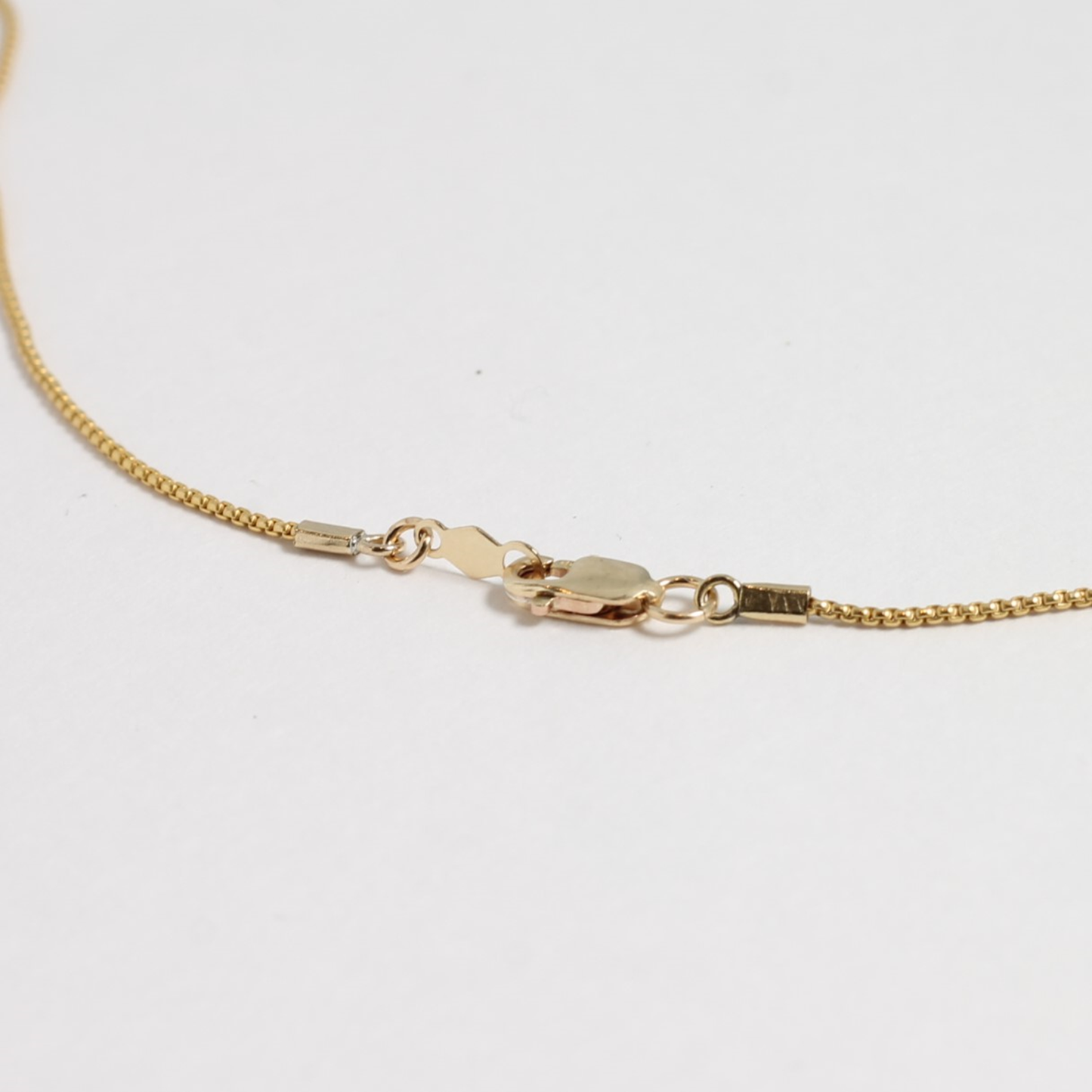 Gold chain necklace on a light gray background